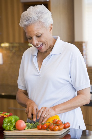Senior woman happily preparing vegetables in a kitchen