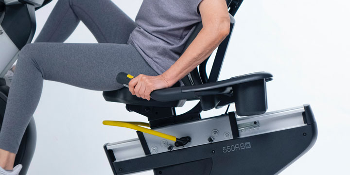 Woman in gray yoga pants pedaling on a recumbent bike