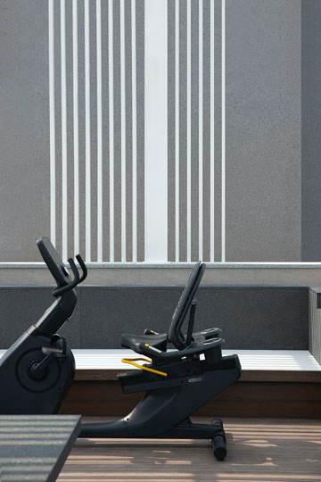 Exercise bike on a balcony with modern gray wall and white lines design in the background