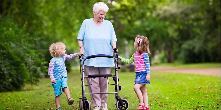 Elderly woman using a walker out in a park with her two grandchildren