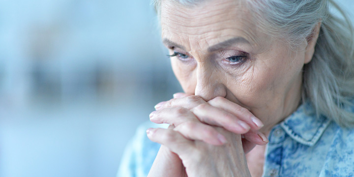 Stressed out senior woman with her face resting on her hands