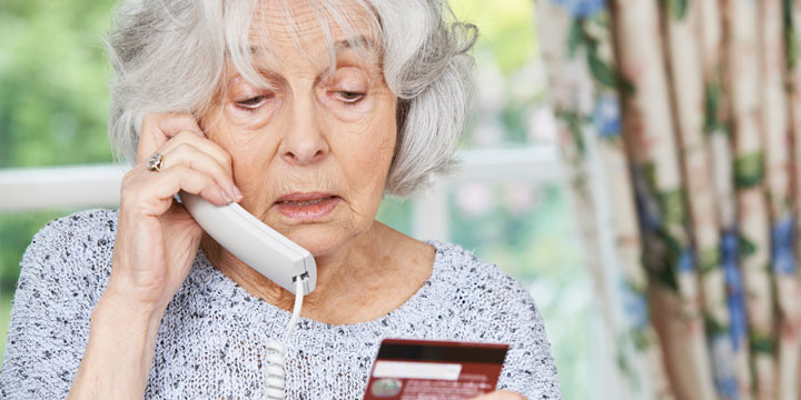 Senior woman talking on the phone with her credit card in hand