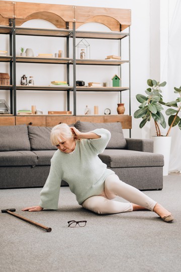 Elderly woman with a cane having neck pain in living room