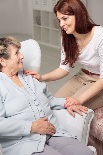 Young woman with elderly woman sitting together in a bright room