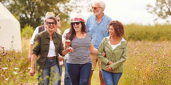 Group of happy older women and men hiking on a path surrounded by wildflowers