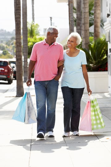 Senior couple walking together holding shopping bags on a sunny day