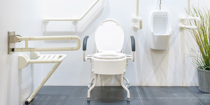 A commode and a urinal surrounded by various grab bars in a white-walled room