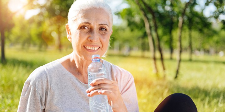 Woman sitting in the park on a sunny day holding a bottle of water