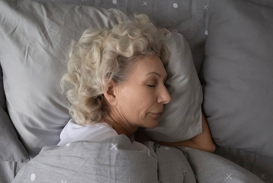 Woman with gray curly hair asleep in a bed