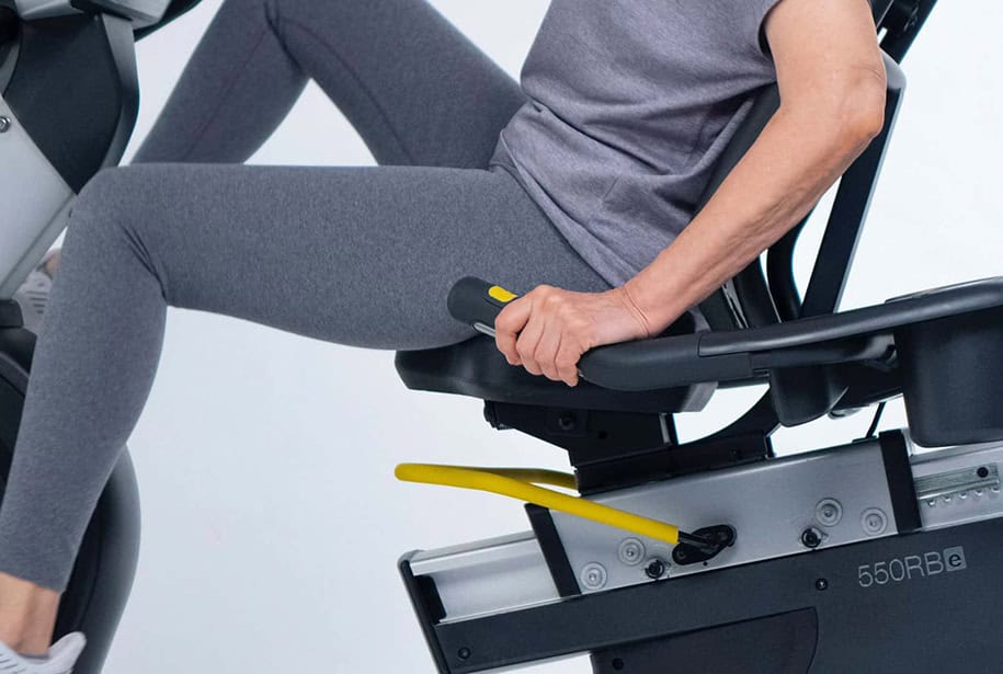 Woman in gray yoga pants pedaling on a recumbent bike