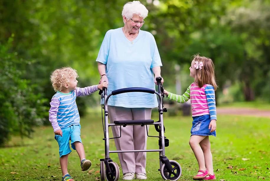 Elderly woman using a walker out in a park with her two grandchildren