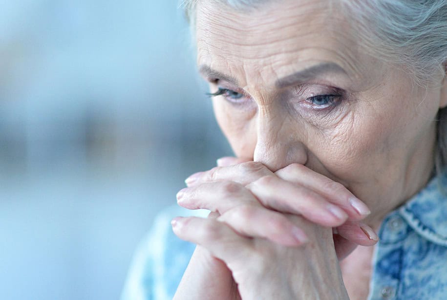 Stressed out senior woman with her face resting on her hands