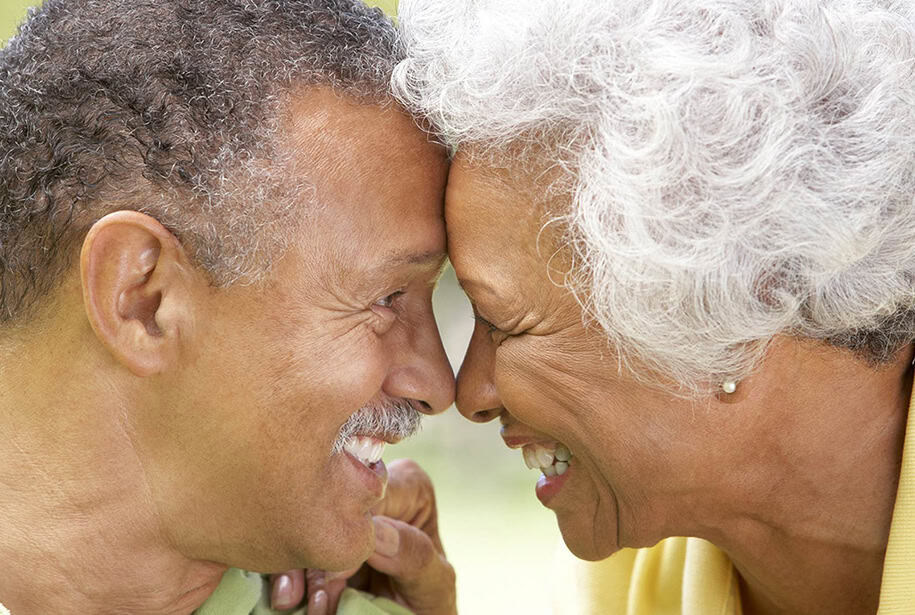 Happy senior couple laughing and touching foreheads while looking into each other's eyes.