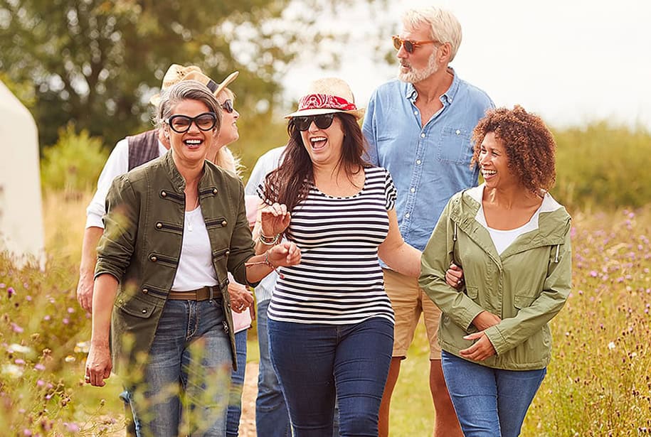 Group of happy older women and men hiking on a path surrounded by wildflowers
