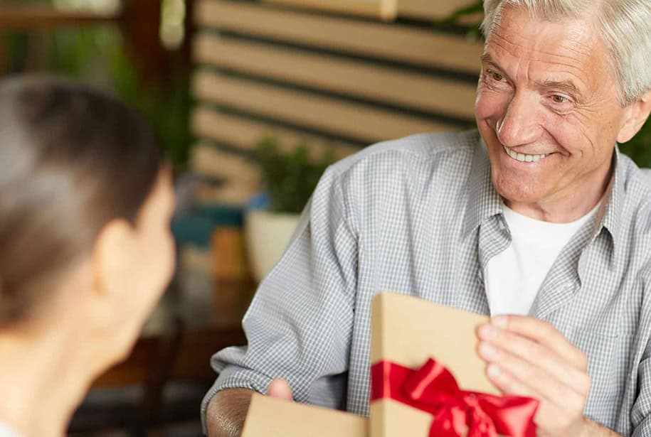 Senior man opening a gift box with a red bow from a family member