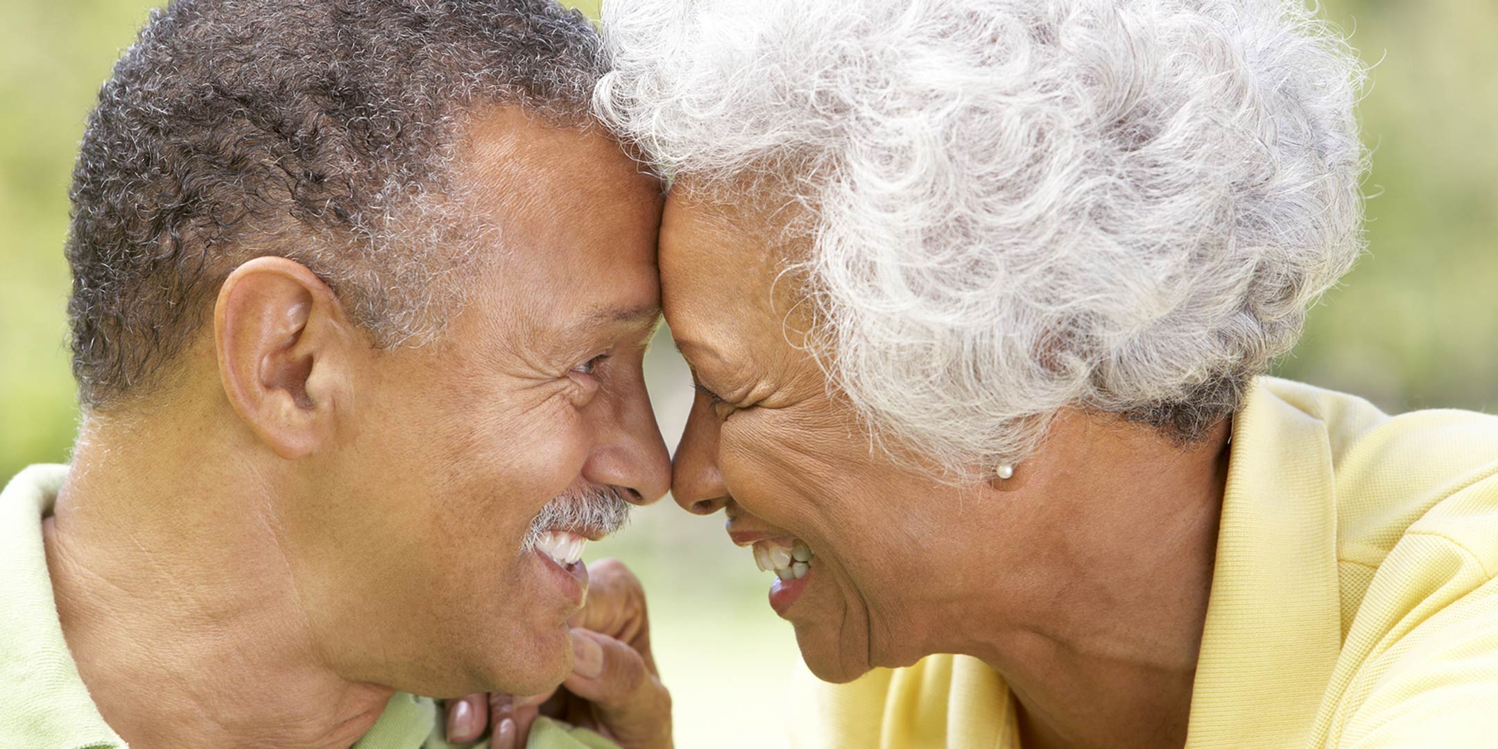 Happy senior couple laughing and touching foreheads while looking into each other's eyes.