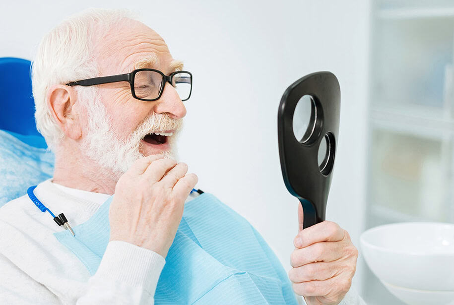 Smiling older woman behind smiling older man embracing him with her head resting on his shoulder