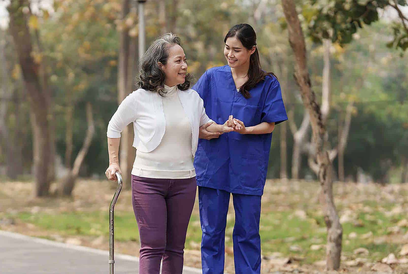 A rehab nurse guides an elderly patient in the safe and effective use of her cane outdoors.